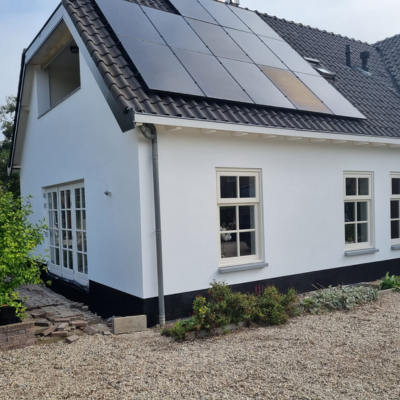 Woning met strak wit buitenstucwerk en zonnepanelen op het dak.