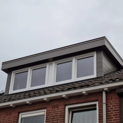 Dakkapel met grijze afwerking en witte kozijnen op een rijtjeshuis.
