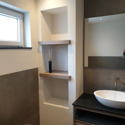 Moderne badkamer met gestucte wanden, ingebouwde nissen en houten accenten.